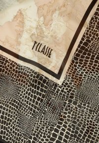 Sciarpa di seta con design di mappa chiara in beige e marrone, contrastata da un motivo a coccodrillo nero testurizzato, rifinita con un bordo nero.