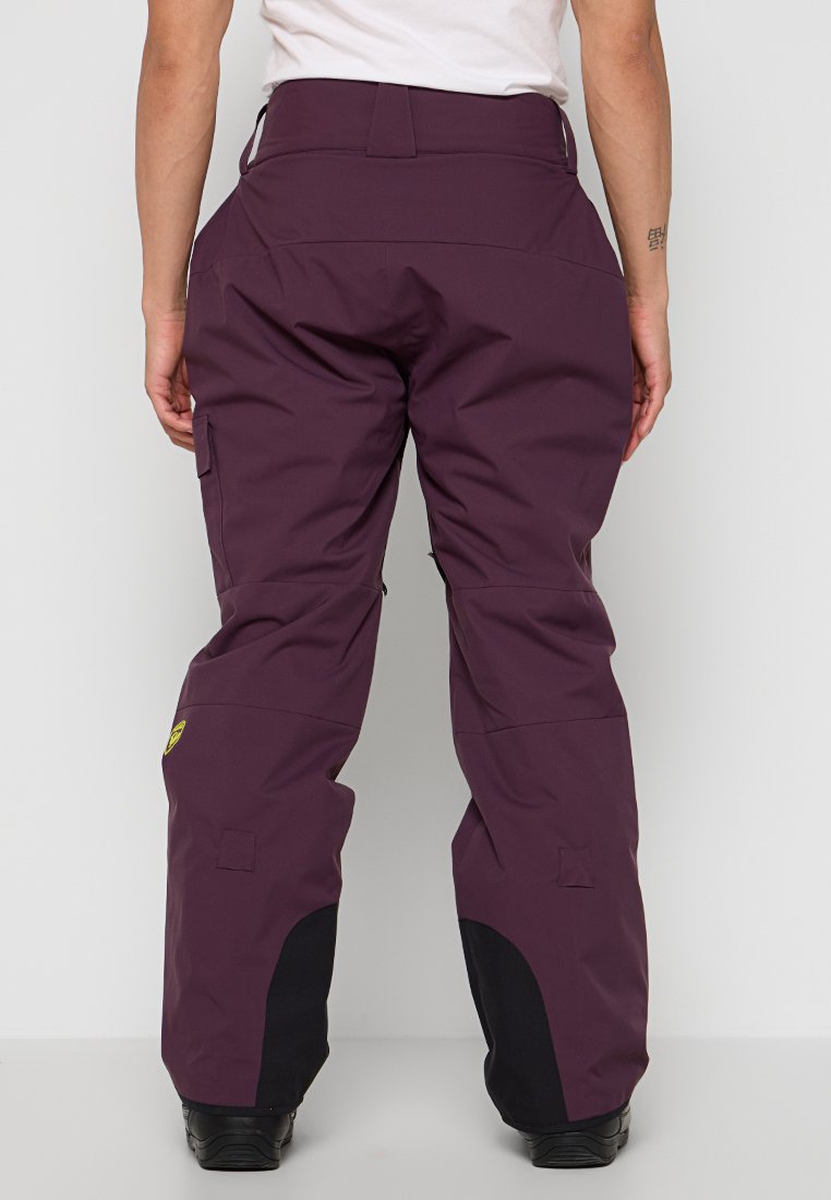 Pantaloni da neve viola con vita alta, rinforzo nero ai polsini e tasche laterali. Realizzati in materiale resistente all'acqua.