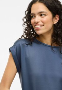 Maglietta a maniche corte, blu navy, con una texture liscia e una vestibilità comoda, caratterizzata da un ampio scollo e maniche arrotolate.