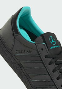 Baskets noires avec une tige texturée, une doublure turquoise et des accents de logo. Dotées d'une semelle en caoutchouc et de détails rayés sur les côtés.