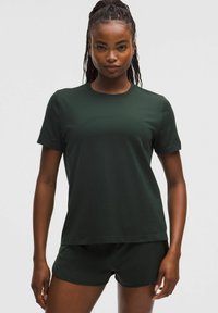 Camiseta de manga corta verde oscura hecha de material texturizado, combinada con pantalones cortos a juego de color verde oscuro. Diseño simple con cuello redondo.