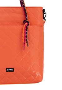 Borsa arancione trapuntata con una finitura liscia, caratterizzata da una maniglia annodata multicolore e una patch con logo nera sul davanti.