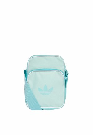 Bolso bandolera de lona azul claro con acentos blancos, que cuenta con un bolsillo frontal con cremallera y un logo grabado en la parte delantera. Forma cuadrada, correa ajustable.
