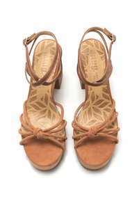 Sandalias de tacón alto de ante marrón con un diseño frontal anudado, correas en el tobillo y un patrón de hojas texturizado en la plantilla.