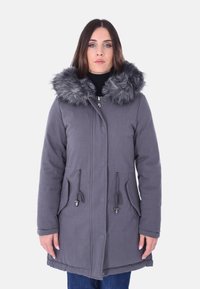 Parka grigia con cappuccio in pelliccia sintetica, chiusura con zip, vita regolabile con cordino e due tasche frontali. Tessuto morbido e texture, con una vestibilità leggermente ampia.