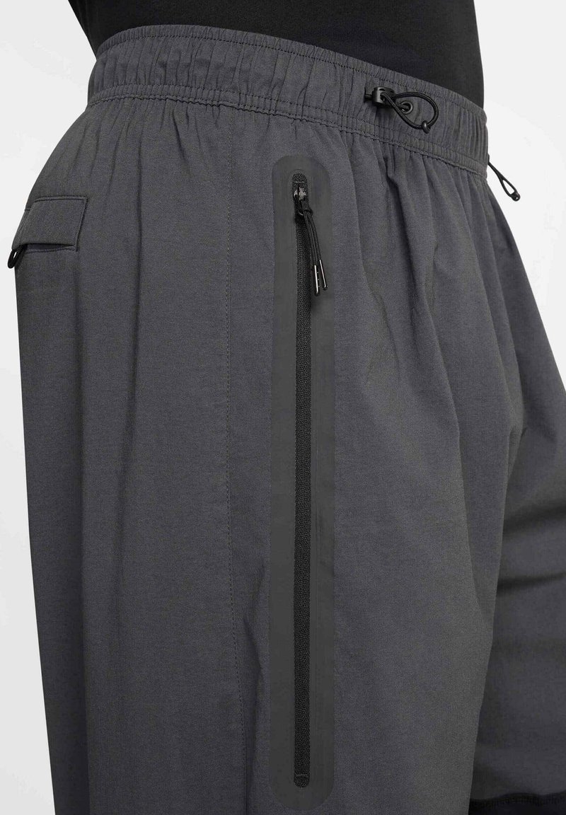 Pantalones cortos grises con una cintura elástica, cordón y bolsillo con cremallera lateral. Presentan una textura suave y un corte holgado para mayor comodidad.