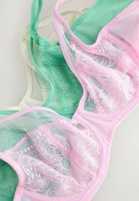Tri čipkované podprsenky v pastelovej ružovej, zelenej a krémovej farbe s jemnými kvetinovými vzormi na svetlom pozadí.