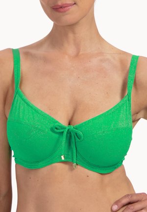 Femme portant un haut de bikini vert vif à fines bretelles et détail de nœud à l'avant, visible du cou au milieu du torse.