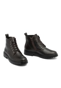 Bottines en cuir marron avec lacets, œillets métalliques, fermeture éclair latérale, semelle texturée et détails de couture contrastants.