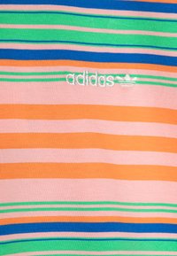Lenteņu t-krekls ar horizontālām joslām oranžā, rozā, zilā un zaļā krāsā. Izšūts balts "adidas" logotips ar trim svītrām uz krūšu daļas.