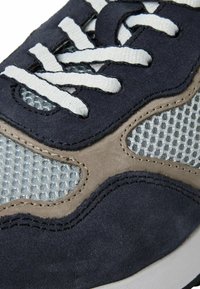 Tenisi din suede bleu marin cu panouri din plasă, sireturi albe și accente bej. Suprafața texturată și detaliile cusute subliniază designul acestora.