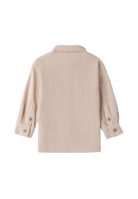 Camisa de manga larga de color beige con cuello doblado y puños abotonados, mostrada desde atrás sobre un fondo blanco.