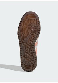 Barna gumitalp, halszálka mintával, kiemelkedő kör- és hatszögletű textúrákkal, az oldalon az "adidas" felirattal.