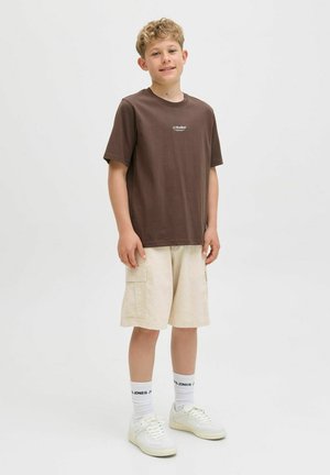 T-shirt en coton marron avec logo, shorts cargo beiges, baskets blanches, et chaussettes avec texte noir. Design simple, coupe décontractée, couleurs sobres.