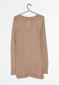 Beige langärmliger Pullover an einem Kleiderständer, mit einem runden Halsausschnitt, gerippten Bündchen und einer mittigen Naht auf der Rückseite. Weiche Textur.