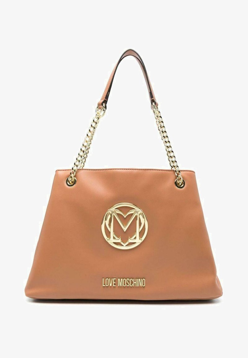 Bolsa tote sintética color beige con una cadena dorada como asa. Presenta un gran logo dorado y el nombre de la marca grabado en la parte frontal. Textura suave.