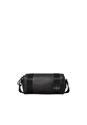 Black cylindrical Calvin Klein duffel bag with branded straps and a shoulder strap on a white background.