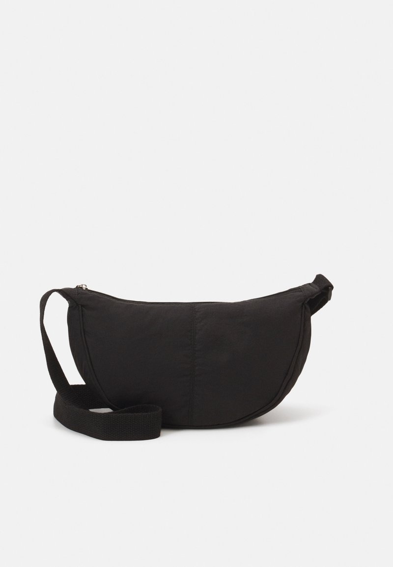 Mala preta de ombro com uma silhueta arredondada. Feita de tecido texturizado, com fecho de zíper e uma alça trançada. Design simples e minimalista.