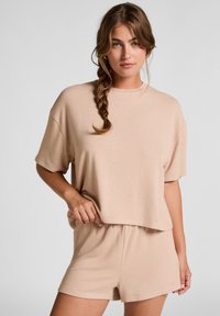 Lichtbruine, korte mouwen top met een ontspannen pasvorm, gecombineerd met bijpassende shorts. Zachte textuur, minimalistisch ontwerp en elastische tailleband.