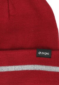 Rote gestrickte Mütze mit einem silbernen horizontalen Streifen und einem schwarzen Etikett mit dem "ZIGZAG"-Logo. Weicher Stoff und faltbares Design.