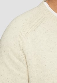 Lichtbeige gebreide trui met een gestructureerde afwerking, met een ronde halslijn en subtiele gespikkelde details door de stof.