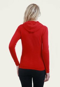 Haut à capuche rouge à manches longues avec un design ajusté et une capuche arrondie. Tissu doux et texturé avec une silhouette simple. Vue arri ère montrée.