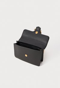 Sac à épaule en cuir noir avec fermoir doré, rabat ouvert et chaîne visible sur fond blanc.