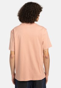 T-Shirt mit kurzen Ärmeln aus weichem Pfirsichbaumwollstoff. Hat einen lässigen Schnitt mit rundem Halsausschnitt und einem kleinen Markentag nahe dem Saum.