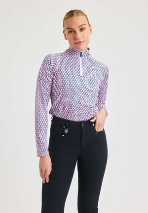 Maglia a maniche lunghe con zip in un motivo geometrico rosa, blu e bianco, abbinata a pantaloni neri con tasche e dettagli metallici.