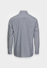 Långärmad skjorta i ljusgrått tyg, med standardkrage, knappdetaljer och en liten trikolor-design på bakkapet.