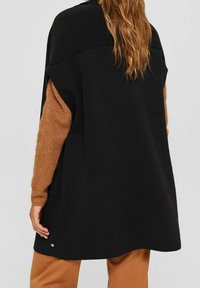 Zwarte oversized trui met bruin gebreide mouwen, met een ronde vorm, een gladde textuur en een kleine zilveren accent bij de zoom.