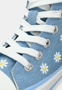 Μπλε τζιν αθλητικό παπούτσι ψηλού τύπου με λευκά κορδόνια, ασημένιες τρύπες για κορδόνια και κεντημένα λευκά μαργαρίτες στις πλευρές. Λείο ελαστικό πέλμα.