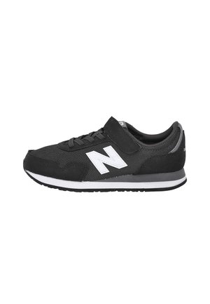Zapatilla deportiva en blanco y negro con tejido de malla, cordones delanteros, tira de velcro y un logo blanco "N" en el lateral.