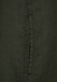 Dunkelgrüner Leinenstoff mit vertikalen Nahtdetails, einem weichen, strukturierten Finish und einem leicht zerknitterten Aussehen.