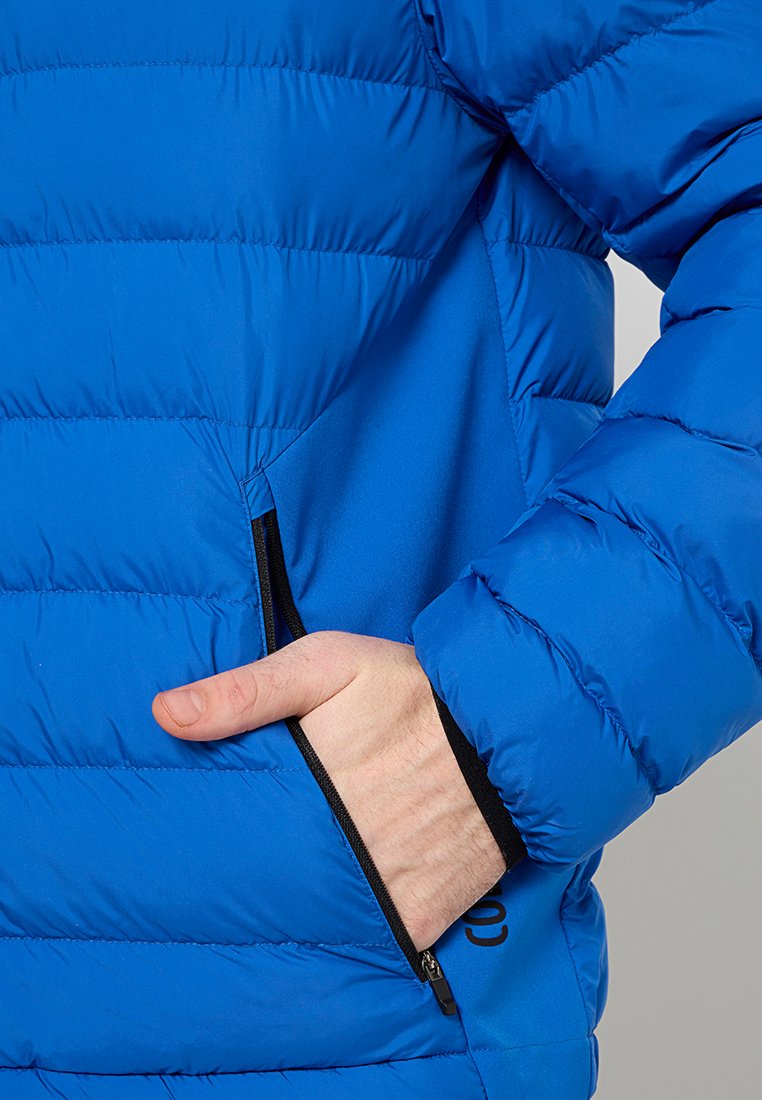 Giacca a vento blu, design trapuntato, con tasca laterale con zip, texture liscia e finitura leggermente lucida.