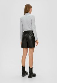 Haut gris à manches longues avec un col rabattu, associé à des shorts en simili cuir noirs taille haute. Comprend deux poches arrière et des bottines.