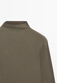 Olive green ribbed turtleneck top with a high collar and long sleeves, featuring a soft texture and tailored fit at the neckline.