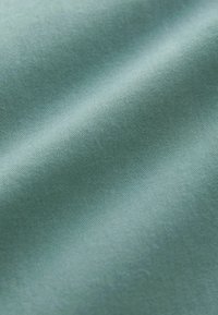 Mekanizirani, teksturirani materijal u umirujućoj teal boji, sa glatkim, sličnim satenu završetkom i suptilnim sjajem te laganim naborima.