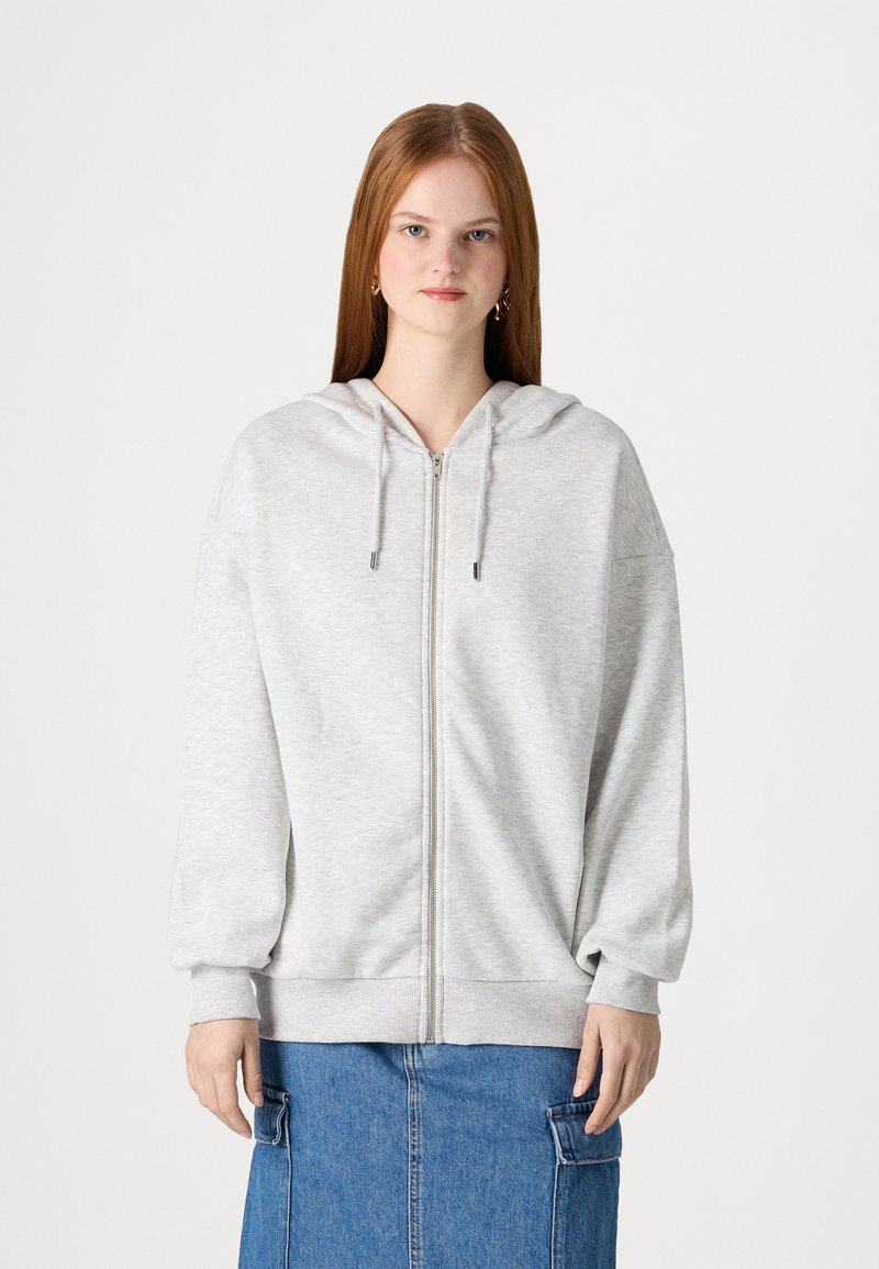 Svijetlosiva dukserica na zip s kapuljačom, rebrastim manžetama i donjim rubom. Mekana tkanina i opušteni kroj stvaraju udoban siluetu.