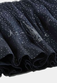 Tessuto di tulle blu navy arricciato all'orlo, con piccoli pois bianchi e motivi argentati luccicanti. Texture morbida e leggera.