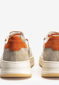 Sneakers with a gray suede body, orange suede accents on the heel, and a white rubber sole with textured detailing.