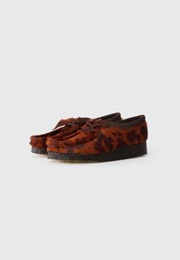 Brown leopard print slip-on shoes with textured fur upper and flat black sole. Features lace closure and rounded toe design.