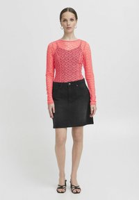 Top in pizzo rosa brillante a maniche lunghe con scollo rotondo, abbinato a una gonna in denim nera. Design semplice, lunghezza a metà coscia, silhouette aderente.