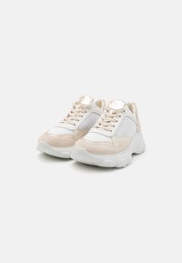 Hvite og beige sneakers med mesh-paneler, semsket detaljer, rund tå og en kraftig hvit såle med teksturdetaljer.