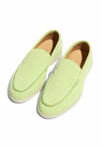 Ein Paar leuchtend grüne Wildleder-Schlupfschuhe mit gestickten Details und hellen Sohlen, von oben auf einem weißen Hintergrund gezeigt.