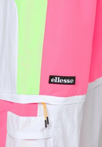 Färgglad vindjacka med paneler i rosa, grönt och vitt. Innehåller en framficka med gul dragsko och 'ellesse'-logotyp i svart.