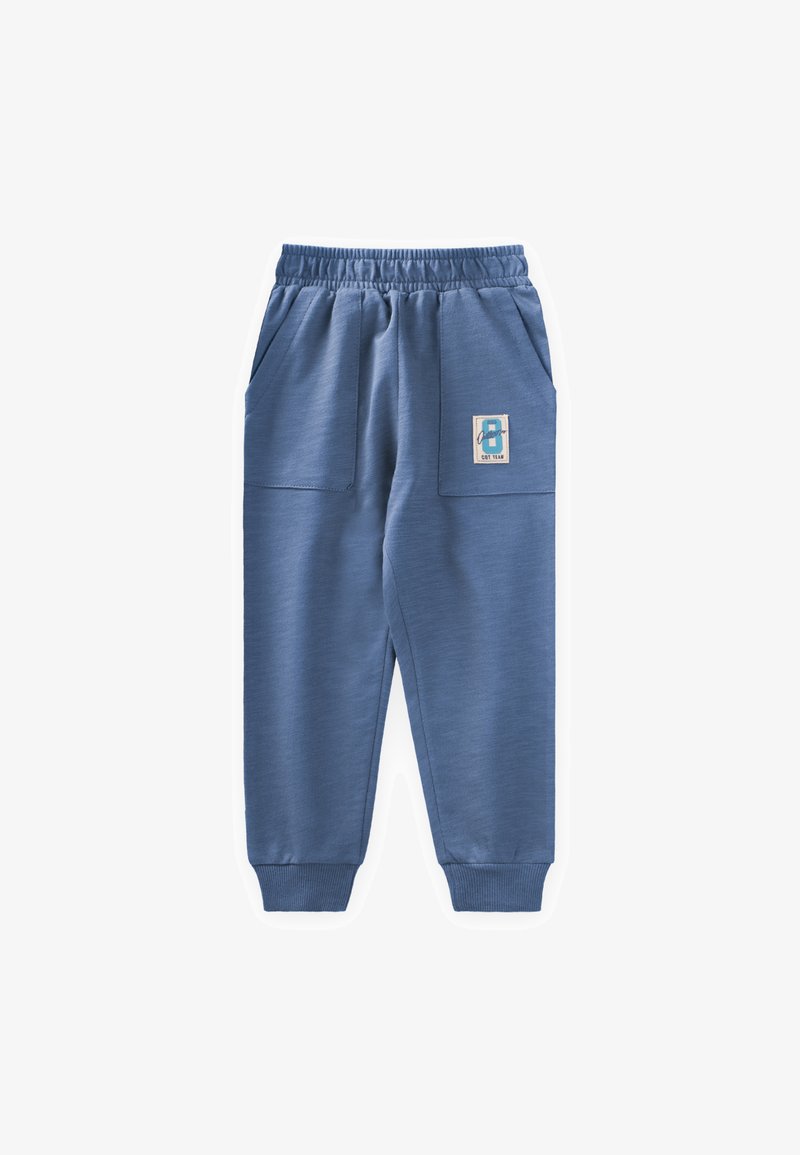 Blaue Jogginghose aus weichem Stoff, mit seitlichen Taschen, elastischem Bund und gerippten Bündchen. Ein Etikett mit der Nummer 8 ist angebracht.