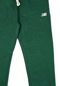 Joggers in cotone verde con vita elasticizzata, cordino bianco e piccolo logo bianco sul coscio. Texture liscia e design aderente.
