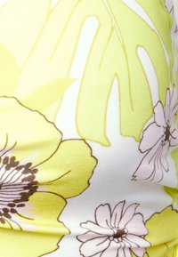 Tecido com padrão floral, apresentando flores amarelas e rosa claro. Textura suave com fundo branco e contornos de folhas verdes.