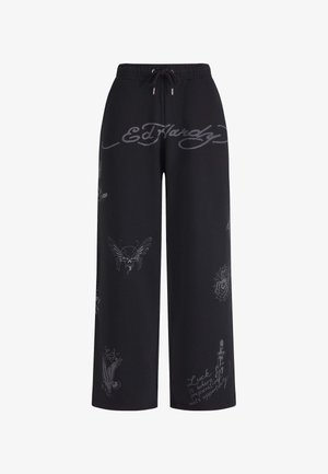 Zwarte wijd uitlopende broek met trekkoord in de taille, met grijs Ed Hardy-logo en tatoeagestijl ontwerpen waaronder een schedel, spinnenweb en adelaar.